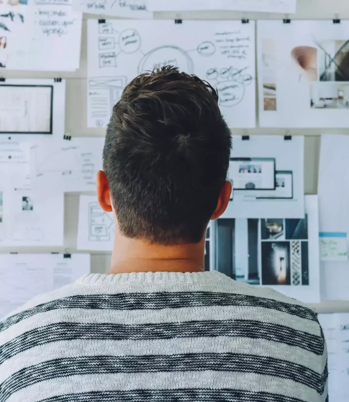 un homme regardant un mur couvert de papier, en reflexion